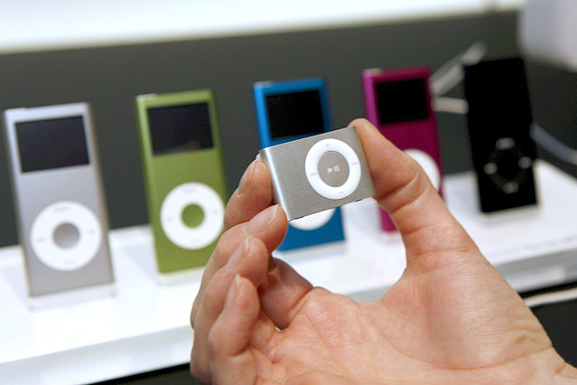 © APA/EPA/John G. Mabanglo Eine hand hält den iPod-Shuffle in die Kamera, im Hintergrund sind mehrere verschiedene iPod-Nanos zu sehen