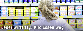 Eine Frau von hinten blickt auf ein Supermarktregal.