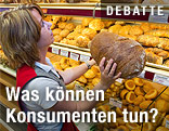 Eine B&auml;ckereiangestellte nimmt einen Laib Brot aus dem Regal.