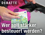 Frau mit Geldb&ouml;rse und einer 100-Euro-Geldnote in der Hand