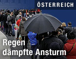Warteschlange mit Regenschirmen