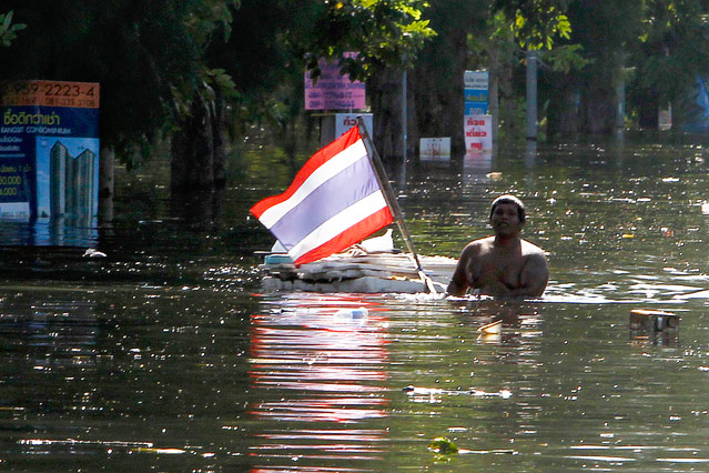 © Reuters/Sukree Sukplang Ein Mann hält im Hochwasser eine thailändische Flagge hoch