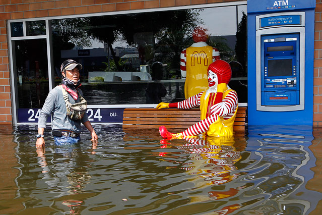 © APA/EPA/Rungroj Yongrit Mann geht durch Hochwasser an einer Figur von McDonalds vorbei