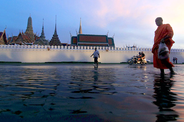 © AP Ein Mönch watet durch eine überflutete Straße vor einem Tempel in Bangkok