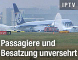 Löschende Feuerwehrautos neben der notgelandeten Boeing