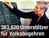 Eine Frau schreibt die Ergebnisse des Bildungsvolksbegehrens auf eine Tafel