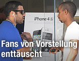 Ein Kunde spricht vor einem iPhone-4s-Plakat mit einem Apple-Mitarbeiter