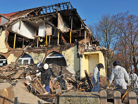 © APA/dpa/Hendrik Schmidt Polizisten bei einem zerstörten Haus
