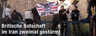 Männer stehen auf einem Zaun und wehen mit Fahnen