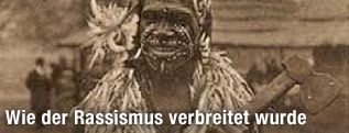Alte, sepiafarbene Postkarte eines "Kannibalen" mit Gesichtsbemalung und Axt