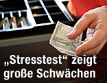 Kassierin hat einen Fünf-Euro-Schein in der Hand