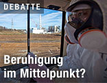Arbeiter in Schutzanzug betrachtet Fukushima aus einem Fenster aus