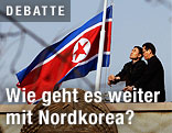 Zwei Männer hissen die nordkoreanische Flagge auf Halbmast