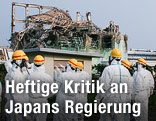 Mitarbeiter der Atomenergiebehörde IAEA blicken auf ein zerstörtes Reaktorgebäude
