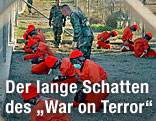 Ein Häftling und US-Soldaten in Guantanamo