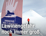 Lawinenwarnschild mit Skifahrer im Hintergrund