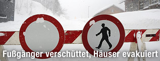 Eingeschneites Verkehrschild zeigt Fahrverbot und Fußgänger