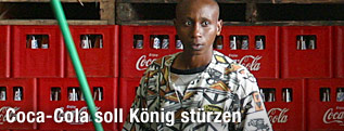 Afrikanischer Arbeiter steht vor Coca-Cola-Kisten