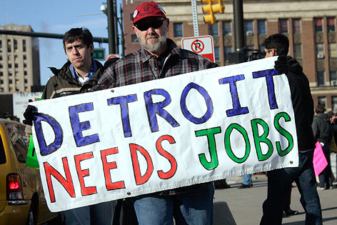 Ein Arbeiter hält ein Schild mit der Aufschrift "Detroit needs Jobs"