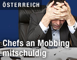 Mann hält sich Hände an den Kopf und sitzt am Schreibtisch