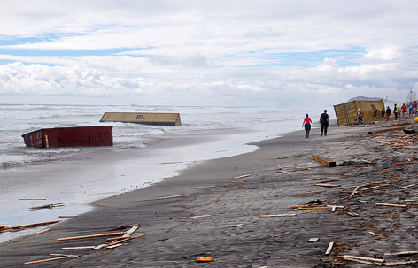 © APA/EPA/AAP/Cleo Fraser Menschen spazieren zwischen angeschwemmten Containern entlang des Waihi-Strandes in Neuseeland