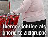 Eine übergewichtige Frau schiebt einen Einkaufswagen