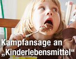 Kind schleckt Löffel mit Pudding ab
