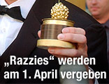 Eine Hand hält einen Golden Raspberry Award