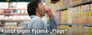 Mann im Pyjama steht im Supermarkt