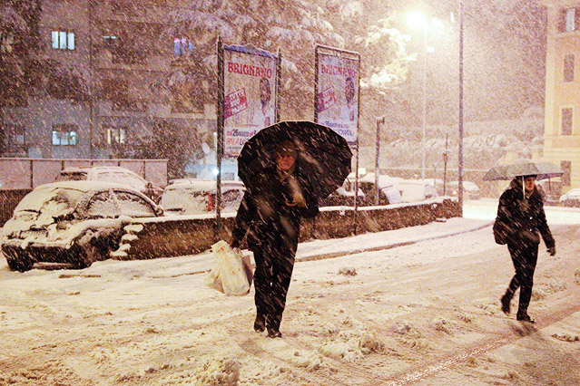 Zwei Frauen mit Regenschirmen stüpafen durch den Schnee in den Straßen Roms