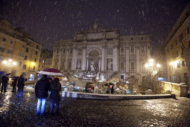 Wenige Touristen stehen mit Schirmen ausgestattet vor dem Trevi-Brunnen