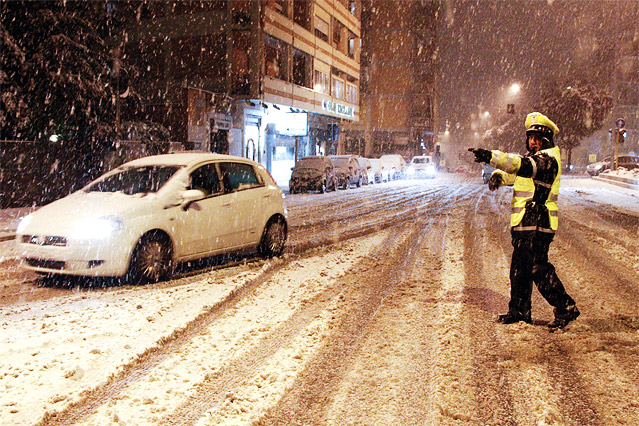 Verkehrspolizist weist ein Auto durch die verschneiten Straßen