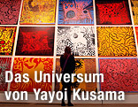 Eine Frau blickt auf ein riesiges Gemälde von Yayoi Kusama