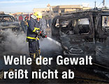 Ein Feuerwehrmann löscht ein qualmendes Autowrack