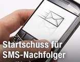 Unbekannte Person hält ein Smartphone mit Brief-Symbol in der Hand