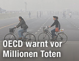 Fahrradfahrer vor einer Smog-Wolke