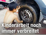 Kleinkind in China bearbeitet einen Autoreifen