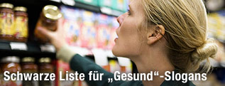 Eine Frau greift nach einem Produkt im Supermarktregal
