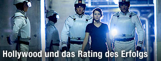 Männer in weißen Uniformen eskortieren Schauspielerin Katniss Everdeen in "Die Tribute von Panem"