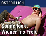 Junger Mann mit nacktem Oberk&ouml;rper sonnt sich auf einem Enzi im Museumsquartier