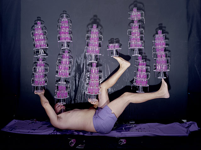 Mann balanziert am Rücken liegend mit Händen und Füßen von Olaf Breuning, Impossible Balance Act, 2008 