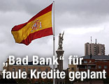 Spanische Flagge vor dunklem Himmel neben einer Kolumbus-Statue in Madrid