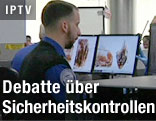 Flughafenmitarbeiter sitzt vor einem Gepäcksscanner