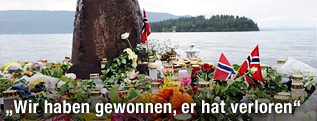 Blumen und Kerzen liegen am Festland, im Hintergrund ist die Insel Ütoya zu sehen