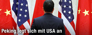Mann steht mit seinem R&uuml;cken zur Kamera, im hintergrund Flaggen der USA und China