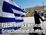 Mann geht über den Platz vor dem griechischen Parlament in Athen daneben weht eine Landesflagge