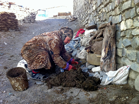 Eine Frau formt Tierkot auf dem Boden in Chynalyg in Aserbaidschan