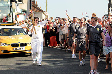 © AP/LOCOG/Yui Mok Charlotte Hodge läuft mit der Olympischen Fackel auf einer Straße