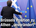 Mann zupft griechische Flagge zurecht