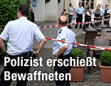 Polizisten neben einer Polizeiabsperrung vor einem Cafe in Wiesloch